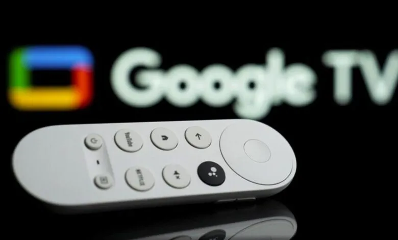 Google TV remote control on a reflective surface with Google TV logo in background.