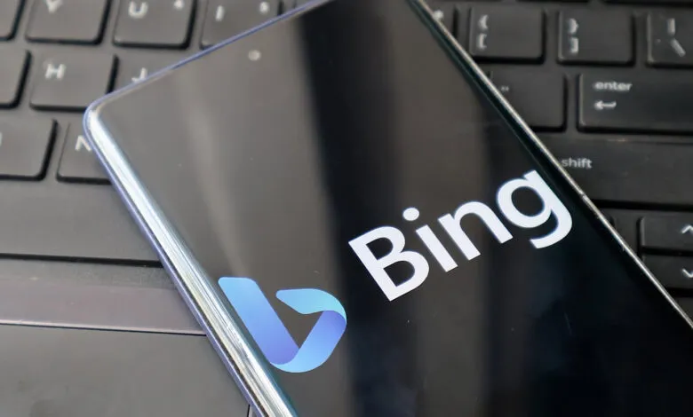 Smartphone displaying the Bing logo resting on a black computer keyboard.