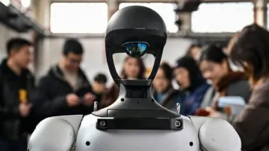 Close-up of a humanoid robot with people in the background.