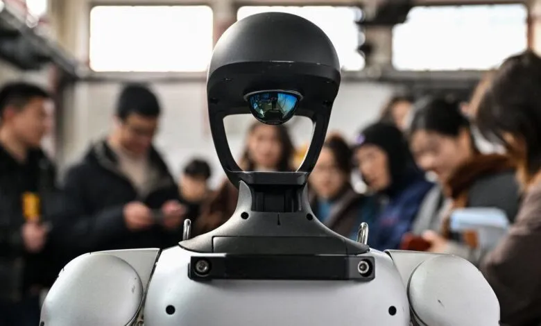 Close-up of a humanoid robot with people in the background.