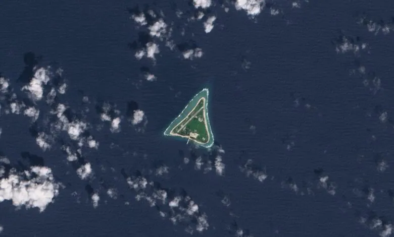 Aerial view of a triangular island with buildings and a runway surrounded by ocean.