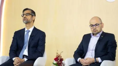 Sundar Pichai and another man sit on stage at a conference.