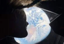 Silhouette of person gazing at Earth from spacecraft window.