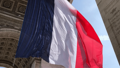 Large French flag draped over the Arc de Triomphe in Paris, France.