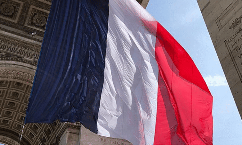 Large French flag draped over the Arc de Triomphe in Paris, France.