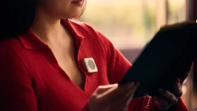 Woman in red sweater with wearable device reading a book.