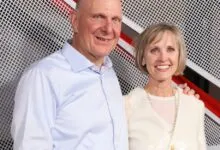 Steve Ballmer and his wife pose in front of a modern backdrop.