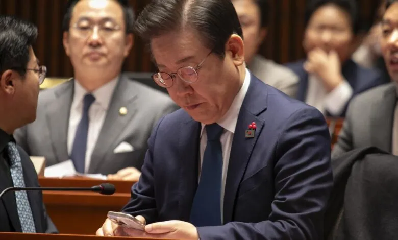 Lee Jae-myung checks his phone during a meeting.