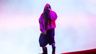 Justin Bieber performs on stage in a pink hoodie and sunglasses.