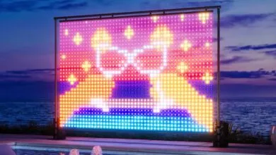 Large LED light wall displays colorful champagne glasses near a pool at dusk.