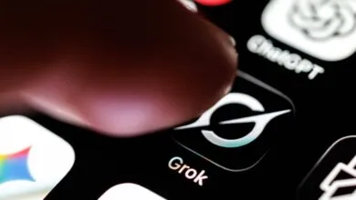 Finger taps Grok app icon on a smartphone screen.