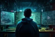 Person in hoodie facing three computer screens displaying circuit diagrams.