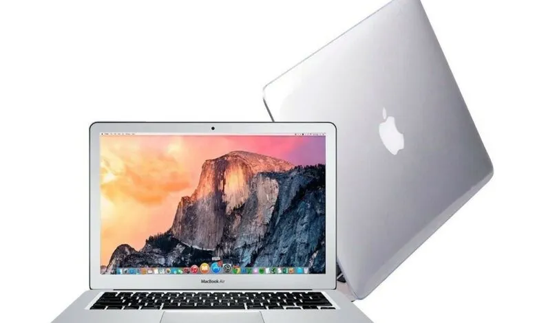 Silver MacBook Air laptop with mountain landscape wallpaper on screen.