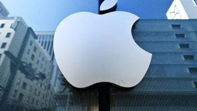 Apple logo on a glass building reflecting city architecture.