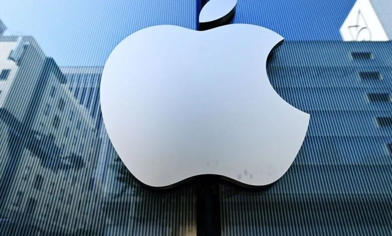 Apple logo on a glass building reflecting city architecture.