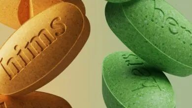 Close-up of orange 'hims' and green 'hers' pills.