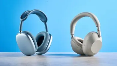Two pairs of wireless headphones, one blue and one white, on a gray surface.