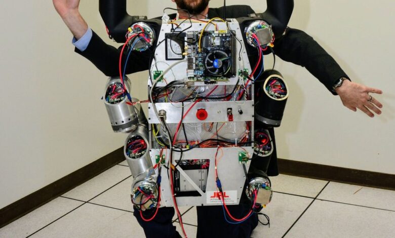 Man wearing complex robotic exoskeleton with exposed wiring and components.
