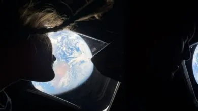 Two silhouettes look out at Earth from a spacecraft window.