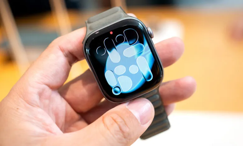 Close-up of a hand holding an Apple Watch with a blue abstract face.