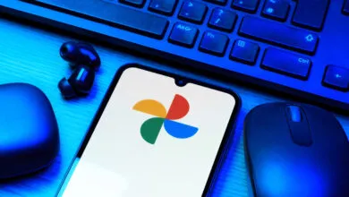 Smartphone displaying Google Photos logo surrounded by tech accessories.