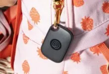 Black tracker attached to a pink strawberry-patterned backpack.