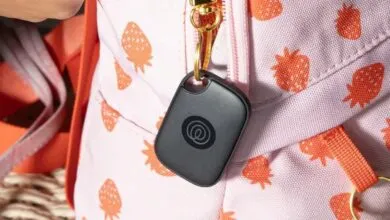 Black tracker attached to a pink strawberry-patterned backpack.