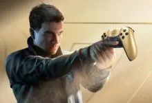 Man holds gold PlayStation 5 controller, aiming like a gun.