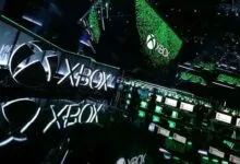 Xbox logo and gaming stations at a conference, showcasing the brand.
