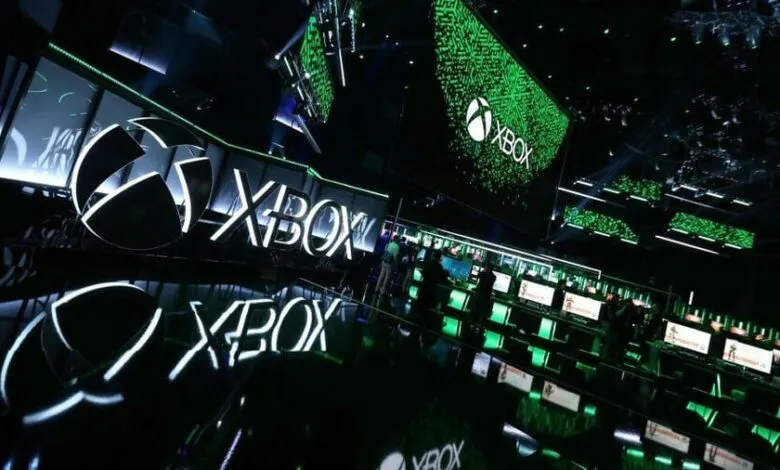 Xbox logo and gaming stations at a conference, showcasing the brand.