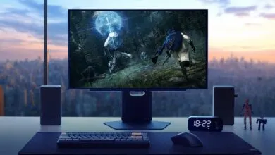 Gaming setup with monitor displaying Elden Ring, keyboard, mouse, speakers, and city view.