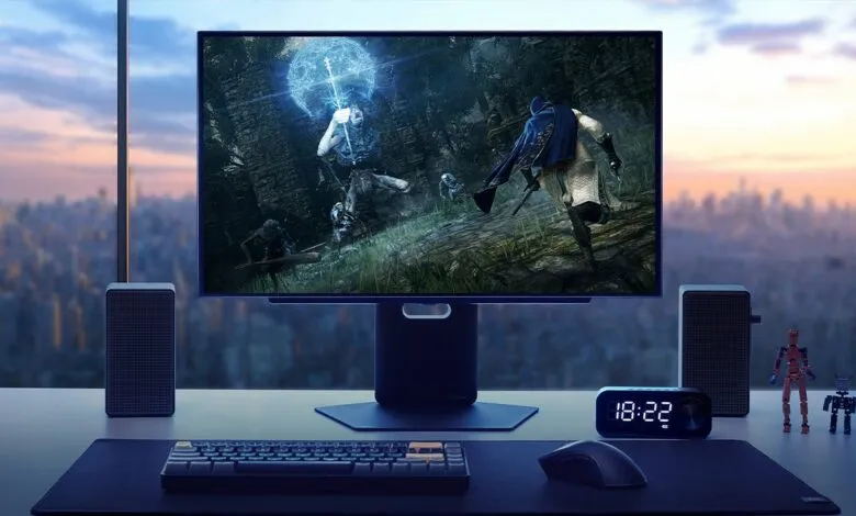 Gaming setup with monitor displaying Elden Ring, keyboard, mouse, speakers, and city view.