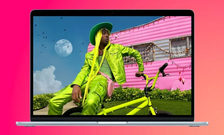MacBook Air screen displays a person on a bike in front of a pink trailer.