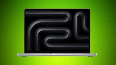 Silver MacBook Pro laptop with black abstract wallpaper on a green background.