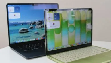 Two Apple MacBook Air laptops, one blue and one green, on a white table.
