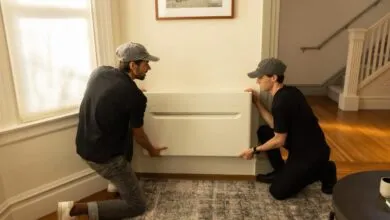 Two men install a sleek, modern air conditioning unit in a home.