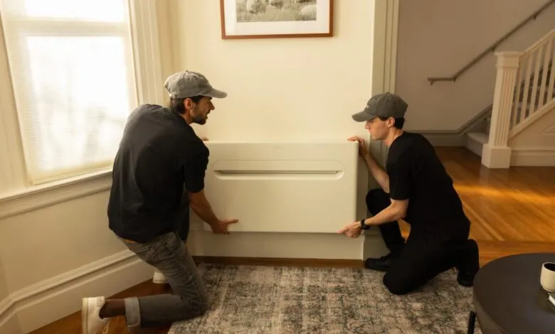 Two men install a sleek, modern air conditioning unit in a home.
