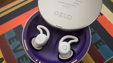 Ozlo sleep earbuds in charging case on colorful surface.