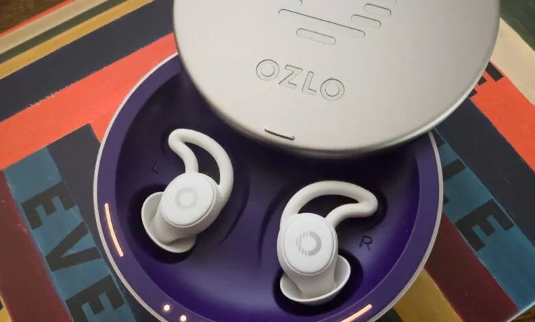 Ozlo sleep earbuds in charging case on colorful surface.