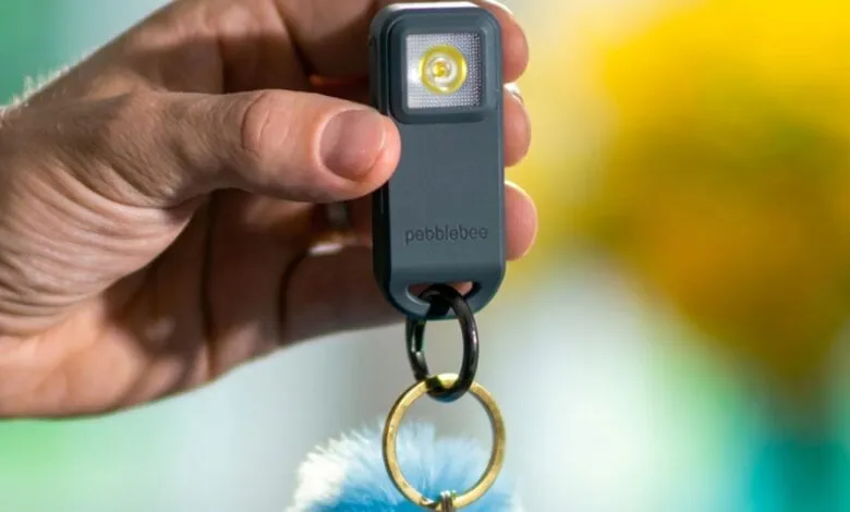 Hand holds Pebblebee Halo 2 key finder with light and keychain.