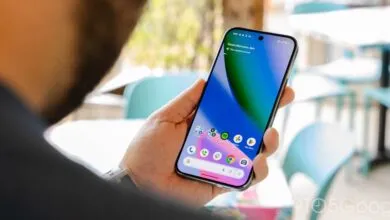 Hand holding a smartphone displaying the home screen with app icons.