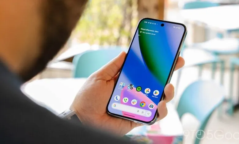 Hand holding a smartphone displaying the home screen with app icons.