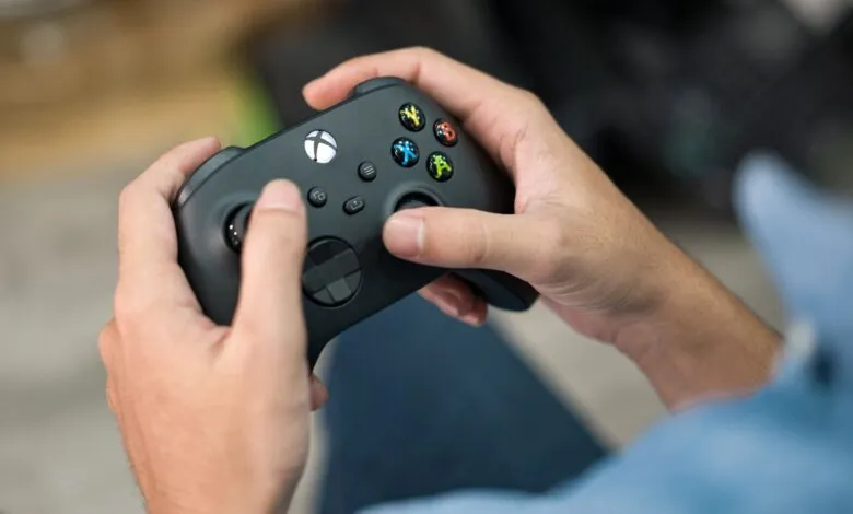 Hands holding a black Xbox controller, ready to play a game.
