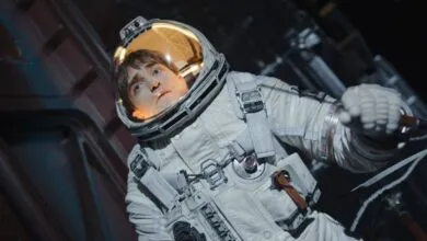 Robert Pattinson in spacesuit looks up with concerned expression.
