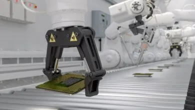 Robotic arm holding a computer chip on a conveyor belt.