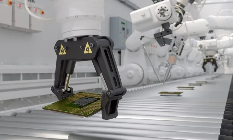 Robotic arm holding a computer chip on a conveyor belt.