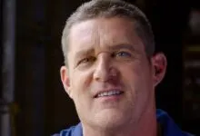 Close-up of a man with short hair and blue eyes looking at the camera.