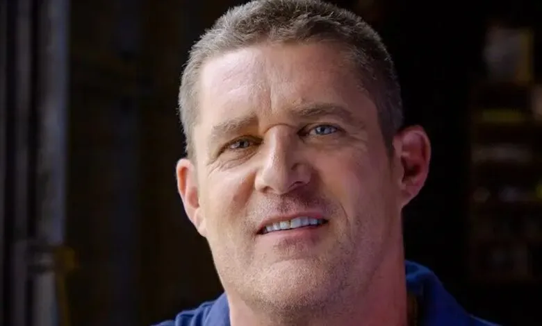 Close-up of a man with short hair and blue eyes looking at the camera.