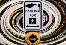 Crosswalk button with hand pushing button, pedestrian symbol, and arrows.
