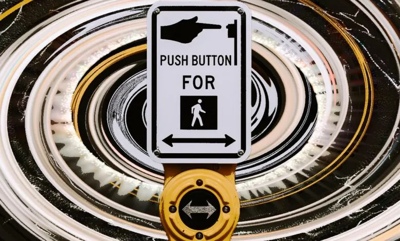 Crosswalk button with hand pushing button, pedestrian symbol, and arrows.